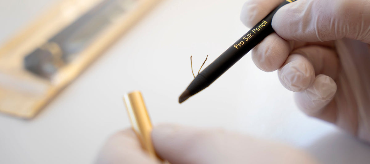 Artist holding a Pro Silk brow pencil and opening the protective cap.