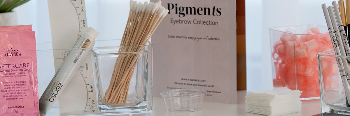 PMU accessories including aftercare, Zensa, Q-tips, color chart, and pigment rings neatly arranged on a counter.